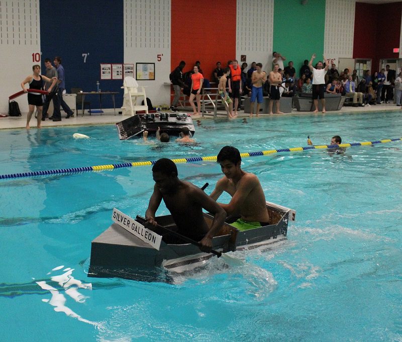 Students paddle a cardboard boat across the pool