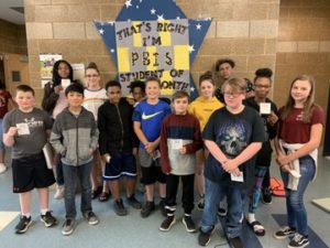 students stand in front of a P.B.I.S. banner