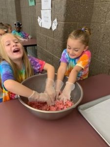 young girls mixing meatballs in a bowl