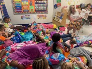 Ms. Ruud reads a book to children on the floor