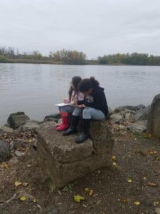 two girls sketching by river