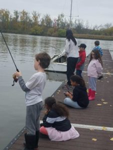 children and teacher fishing off dock