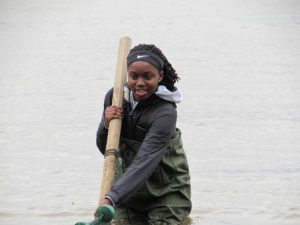 student wading in river and holding seine net