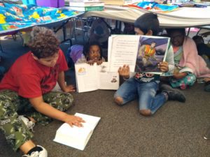 elementary students read together in blanket forts
