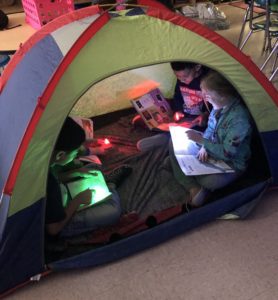 elementary students read together in a tent in the classroom