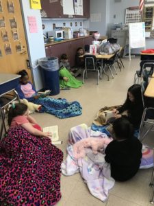 elementary students read under blankets
