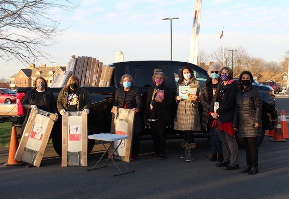 school staff preparing to distibute folding desks in parking lot