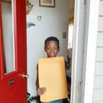 elementary student receives envelope with a certificate and t-shirt