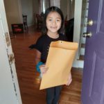 elementary student receives envelope with a certificate and t-shirt