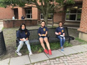 three elementary students seated on bench enjoying donuts