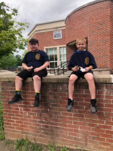 two elementary school boys outside seated on a brick ledge