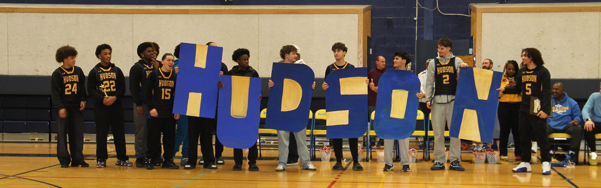 Boys Varsity Basketball team holding up HUDSON letters